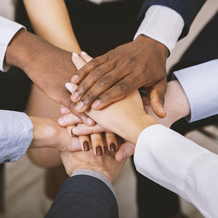 Multiethnic corporate team stacking hands together in office